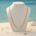 Collier doré perle sur présentoir